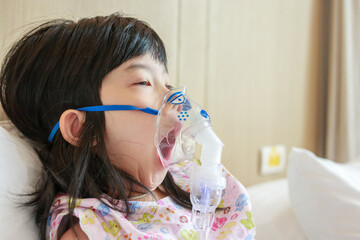 Sick little asian girl inhalation with nebulizer for respiratory treatment - obrazy, fototapety, plakaty