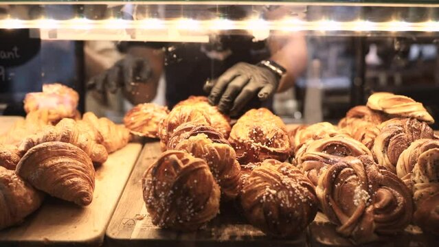 Stockholm, Sweden A server in a cafe fills a display case with sweet buns like cinnamon rolls and croissants. 