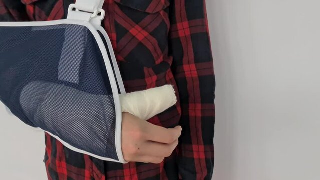 Closeup of sling on teenage man's broken arm to worn during rehabilitation. Child male patient with immobilizer after car accident or sports injury