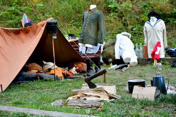 A view of a military themed camp with numerous weapons, suits, uniforms, metal equipment, bags, pouches and other utensils presented for display seen on a sunny summer day in Poland