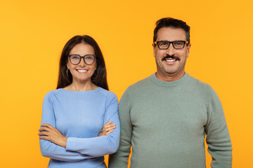 Happy european old couple in glasses, smiling and confidently standing with arms crossed