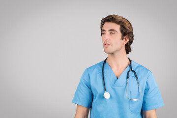 Serious man nurse in blue uniform looking at free space, isolated on grey studio background