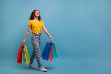 joyful eastern woman walking with shopping bags in her hands