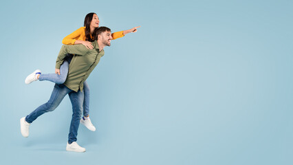 Man giving piggyback ride to woman, pointing at free space