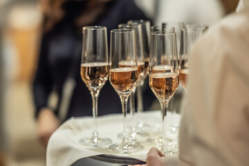 A young waiter holds a plate with champagne or prosecco as a welcome drink at a hotel event