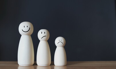 smile face on wooden figure out of line from sad face with copy space for positive mindset selection concept.