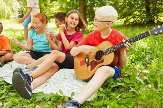 Disabled boy playing guitar with friends - Powered by Adobe