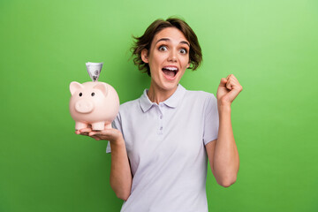 Photo of cheerful girl hold piggy bank collect coins cash rejoice wealth success raise hands fist...