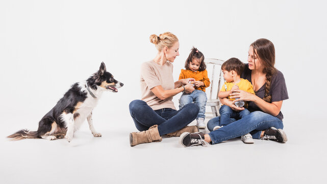 Gay family with their two daughters and a border collie dog on white background