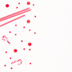 Christmas decoration: candy cane and confetti on white background. Flat lay, top view. New year, copy space