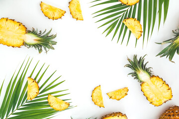 Tropical frame of sliced pineapple and palm leaves on white background. Flat lay, top view.