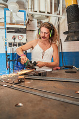 Energetic longhaired carpenter wearing headphones is labouring in workshop