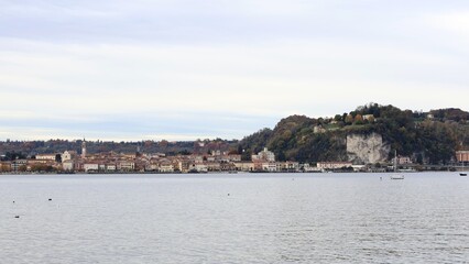 Fototapeta na wymiar View from lake front of Arona, Lake Maggiore, Piedmont, Italy. November 2023 cloudy day.