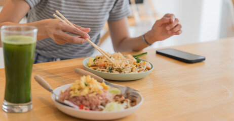 Obraz na płótnie Canvas Asian Girl  eating Thai food in kitchen counter Home delivery food feeling happy 