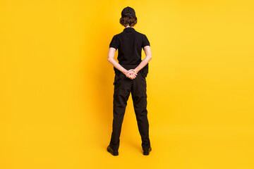 Full body rear photo of police girl standing hold hands behind back isolated on yellow color...