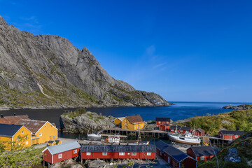 Nusfjord fishing village in Lofoten, Norway, presents a picturesque ensemble of traditional red and...