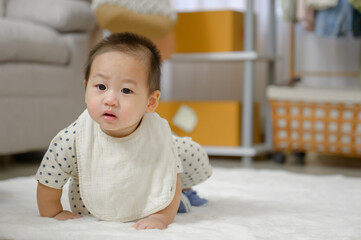Asian baby boy Crawling on the carpeted floor in the living room and baby looking at the camera and playing alone in the room at home.