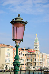 Venetian streetlight and Grand canal palaces with bell tower of St Mark's Basilica at background. Venice, Italy.