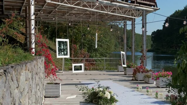 Outdoor wedding ceremony setting with flowers and greenery on either side of the aisle at the riverfront pier.