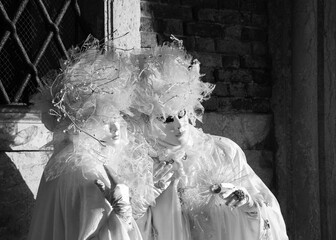 Valentine day in Venice. Two fluffy white masks in St Mark's Square square during the traditional Carnival in Venice, Italy. Black white historic photo