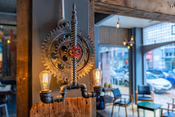 An image of a contemporary industrial gear, sprocket, light fixture mounted to a wall 