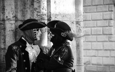 Valentine day in Venice. Two masks in love near Doge's Palace in St Mark's Square during traditional Carnival in Venice, Italy. Black white historic photo.