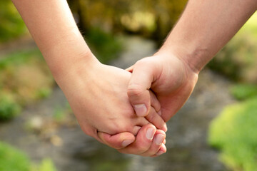 Man's hand firmly holding the female against the background of the stream