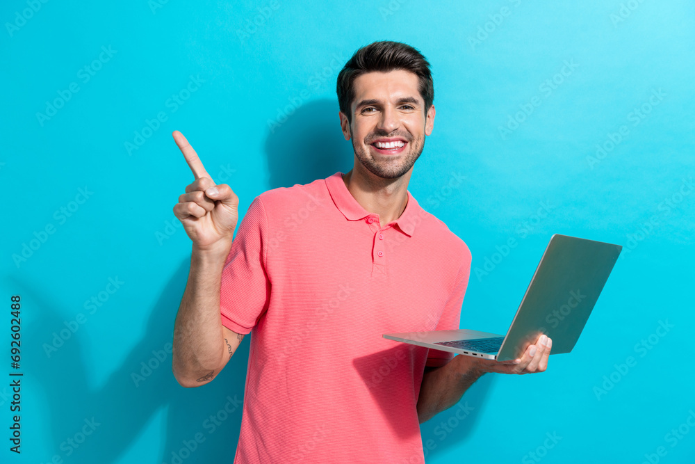 Poster portrait of young guy in pink t shirt works at office point finger empty space with netbook software