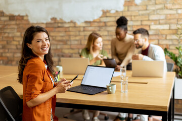 Business woman working on laptop with her young multiethnic startup team working in the modern office