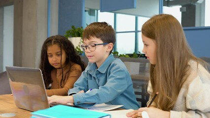 Multiracial children junior students classmates learning online elementary education program class gathered at desk