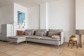Fototapeta na wymiar Corner sofa with cushions and picture in smart apartment