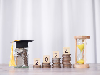 Study goals. Hourglass, Glass bottle with graduation hat and wooden block with number 2024 on stack...