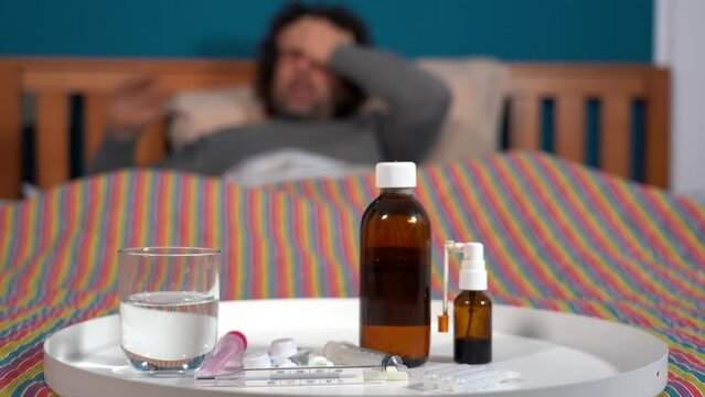 4o year old men sick at home with fever -staying in bed at home with flu and taking antibiotic medicine to treat fever after experiencing fever with thermometer  Covid-19 Coronavirus epidemic 