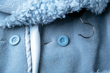 Fragment of a fur coat made of blue sheep's wool with buttons and a hanger