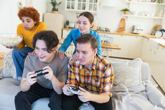 Home party. Cheerful group of friends playing video games at home. Happy diverse group buddies having fun together indoor. Friendship leisure entertainment concept. Young best friends enjoying weekend