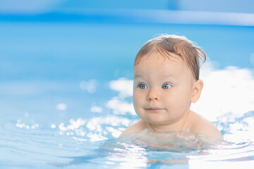 Fototapeta na wymiar Portrait happy baby girl in swimming pool, teaching small swimmer. Concept healthcare sport for infant