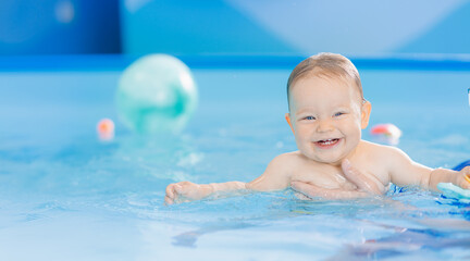 Fototapeta na wymiar Teaching small swimmer happy baby girl in swimming pool. Concept healthcare sport for infant