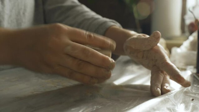 Women's hands knead dense clay for working on a potter's wheel. Making crafts from clay. Hobbies and creativity.