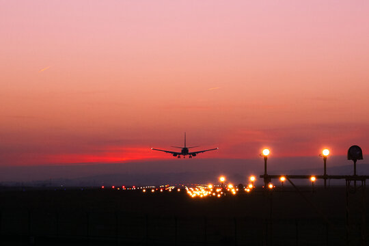 Plane lands at an airfield on the background of red clouds