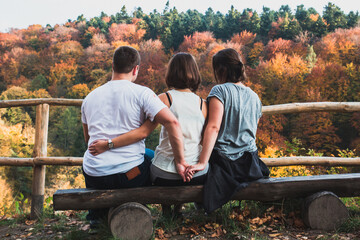Three young people are sitting on a bench, a guy cheating on his girlfriend - 692623204