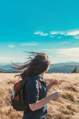 Young girl with flying in the wind hair enjoys the hiking, nature and autumn mountains - 692624069