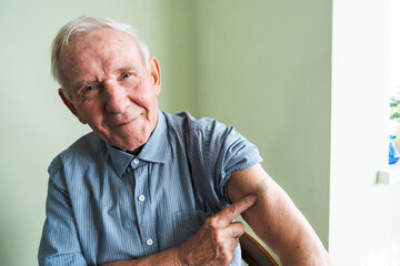 Happy old grandfather at his home. An adult pensioner sits against a wall with a bandage after...