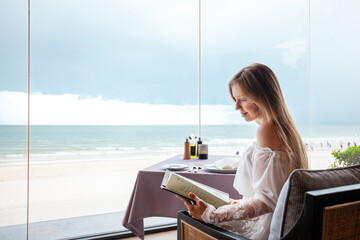 Young adult enjoying menu selection, seaside fine dining, panoramic ocean backdrop, relaxed beach...