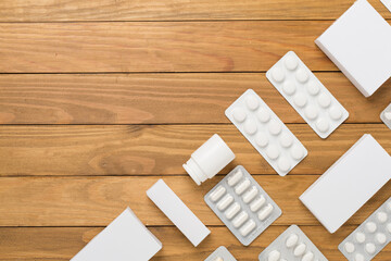 Flat lay with different pills in blister packaging and boxes and on wooden background