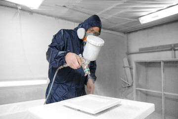 Professional worker staining wood furniture with spray gun - obrazy, fototapety, plakaty