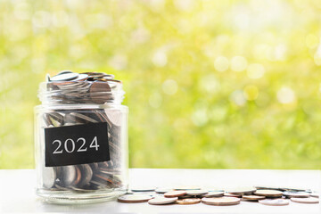 Coins in glass jar. Collect money for future, saving and investment in 2024 concept. Closeup, copy space - obrazy, fototapety, plakaty