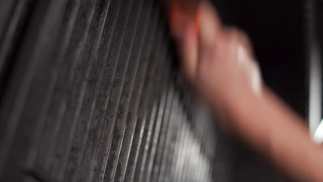 Close-up of a man's hands using a metal brush to clean a dirty grill