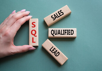 SQL - Sales Qualified Lead. Wooden cubes with words SQL. Businessman hand. Beautiful grey green...