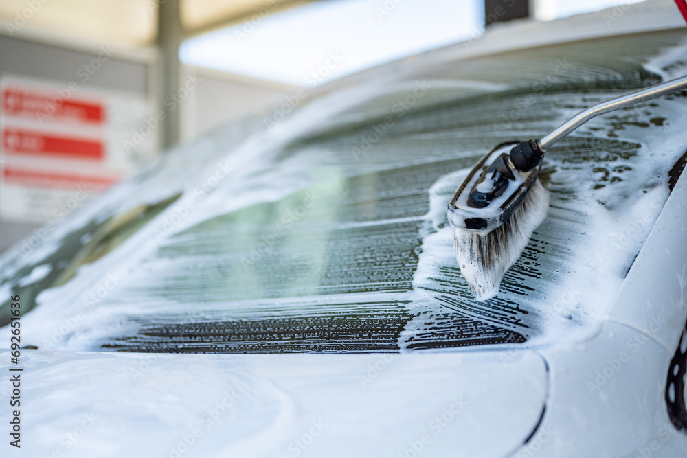 Sticker Manual car wash with white soap, foam on the body. Washing Car Using High Pressure Water.