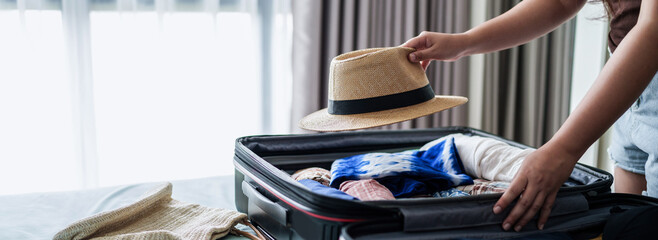 Woman packing suitcase at home preparing to summer travel trip